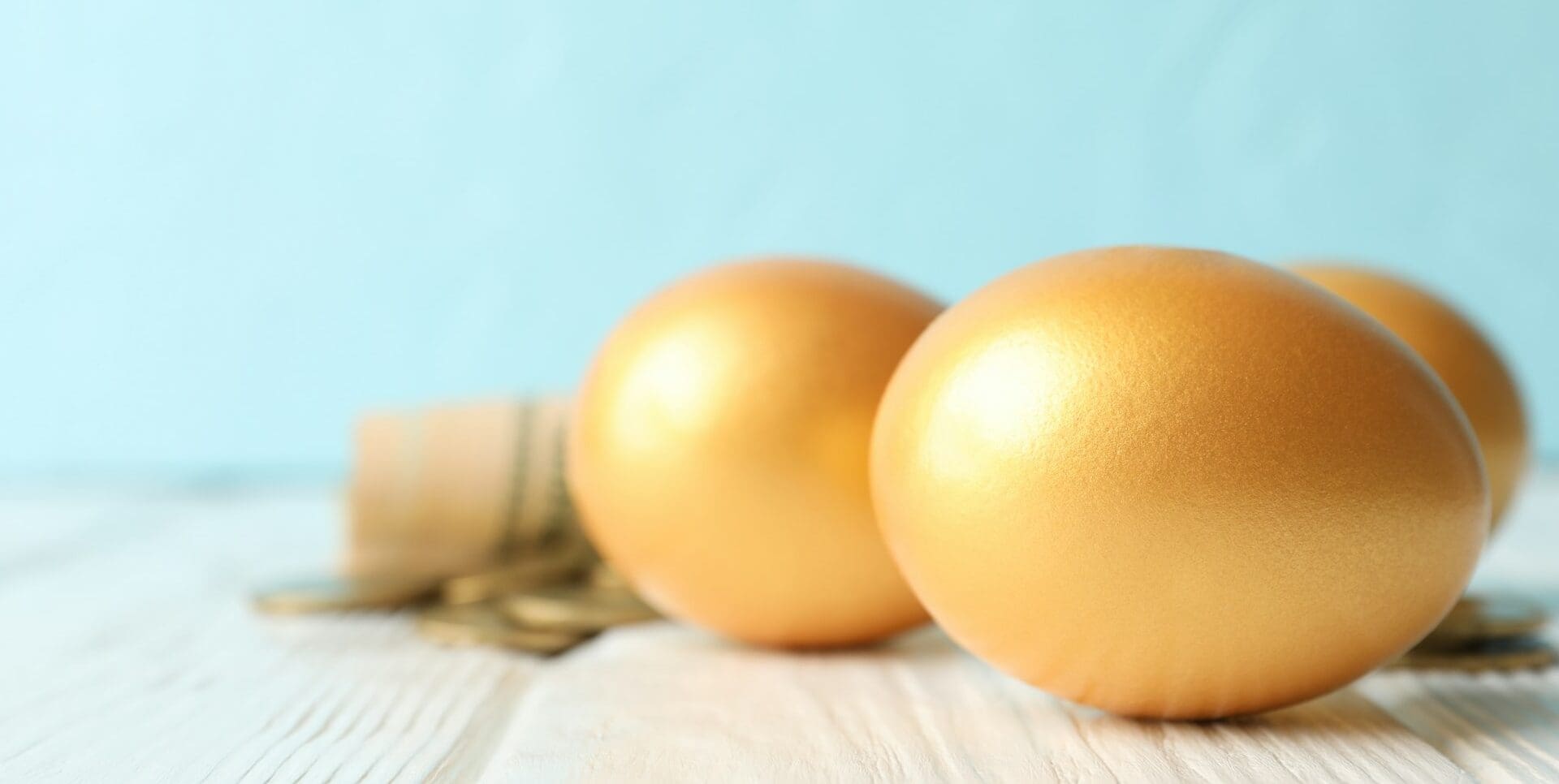 Golden eggs and money on against blue background, space for text