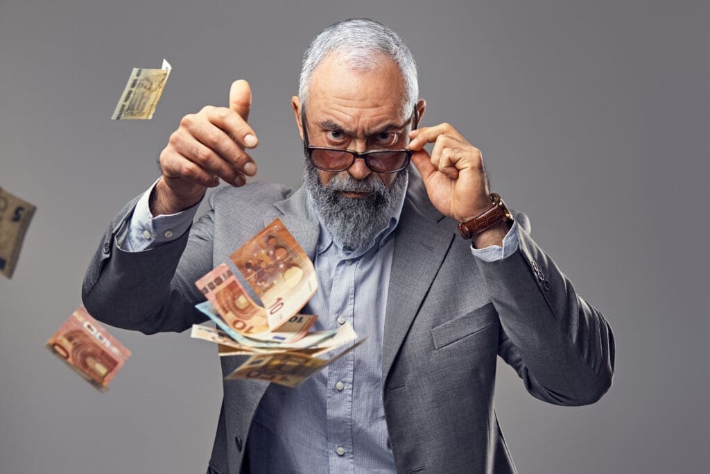 Portrait of serious old business person dropping money looking at camera.